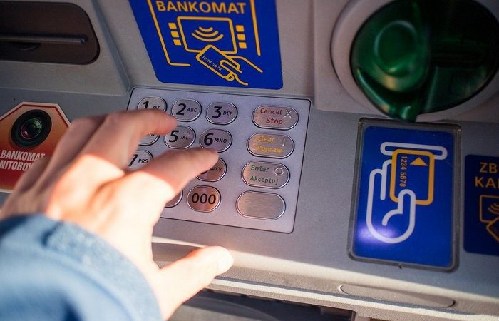 Человек вводит ПИН-код на клавиатуре банкомата