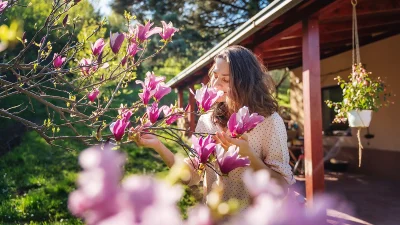 Девушка вдыхает аромат розовой магнолии в весеннем саду