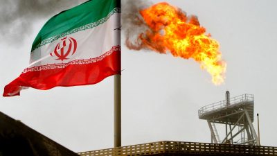 Флаг Ирана на фоне горящего газового факела на нефтяном объекте