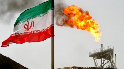 Флаг Ирана на фоне горящего газового факела на нефтяном объекте