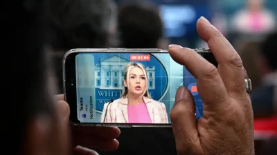 Каролин Ливитт на экране смартфона во время брифинга в Белом доме