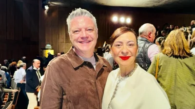 Испанский предприниматель г-н Дорадо и его супруга писательница Эстела Сантьяго улыбаются в зрительном зале театра на фоне других зрителей.