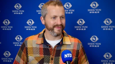 Британский художник Снелл дает интервью на фоне логотипа Shen Yun