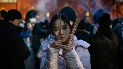 Женщина сжигает ароматические палочки и молится в храме Юнхэ, также известном как храм Ламы, в Пекине, 1 января 2026 года.