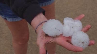 Человек держит три гигантские градины, выпавшие во время катаклизма в США