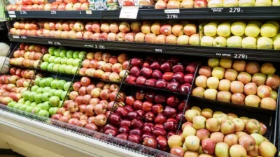 Прилавок с рядами яблок разных сортов в продуктовом магазине