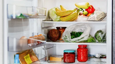 Открытый холодильник с полками, заполненными овощами, фруктами и готовой едой для демонстрации правил хранения.