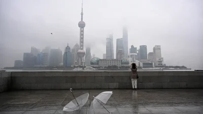 Панорама Шанхая в густом тумане с зонтами на набережной