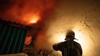 Нефтебаза в огне, пожарный борется с пламенем.