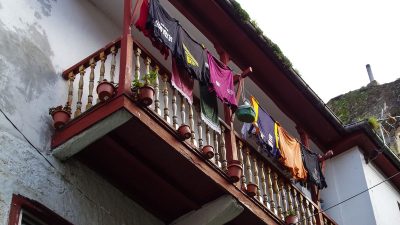 Развешанное на веревках белье на открытом деревянном балконе жилого дома.