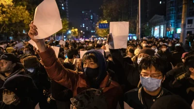 Протестующие поднимают белый лист бумаги в знак протеста против цензуры во время демонстрации против строгих мер по борьбе с COVID-19, введённых в Китае, 27 ноября 2022 года.