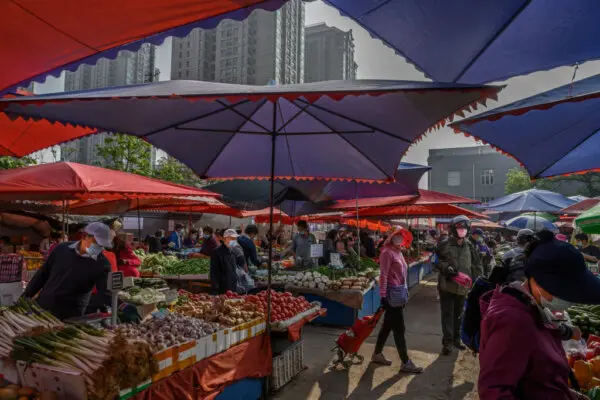 Продавцы и покупатели китайских фруктов и овощей в защитных масках на местном рынке под открытым небом в Пекине, 30 апреля 2020 года.