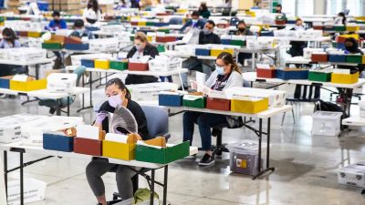 Люди обрабатывают бюллетени на участке регистрации избирателей в Лос-Анджелесе на территории ярмарки в Помоне, штат Калифорния, 31 августа 2021 года.