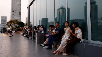 Люди отдыхают на террасе торгового центра в час заката в центральном деловом районе Пекина, Китай, 11 августа 2025 года.