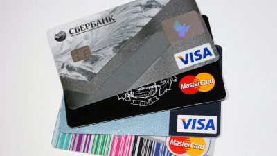 Банковские карты Visa и Mastercard платежных систем на фоне карты Сбербанка, вывод из оборота в России.