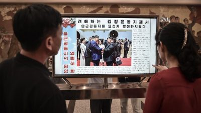 Люди читают сайт «Нодон синмун», на котором опубликована новость о визите Си Цзиньпина, на станции Кэсон Пхеньянского метрополитена в Пхеньяне, 9 июня 2026 года.
